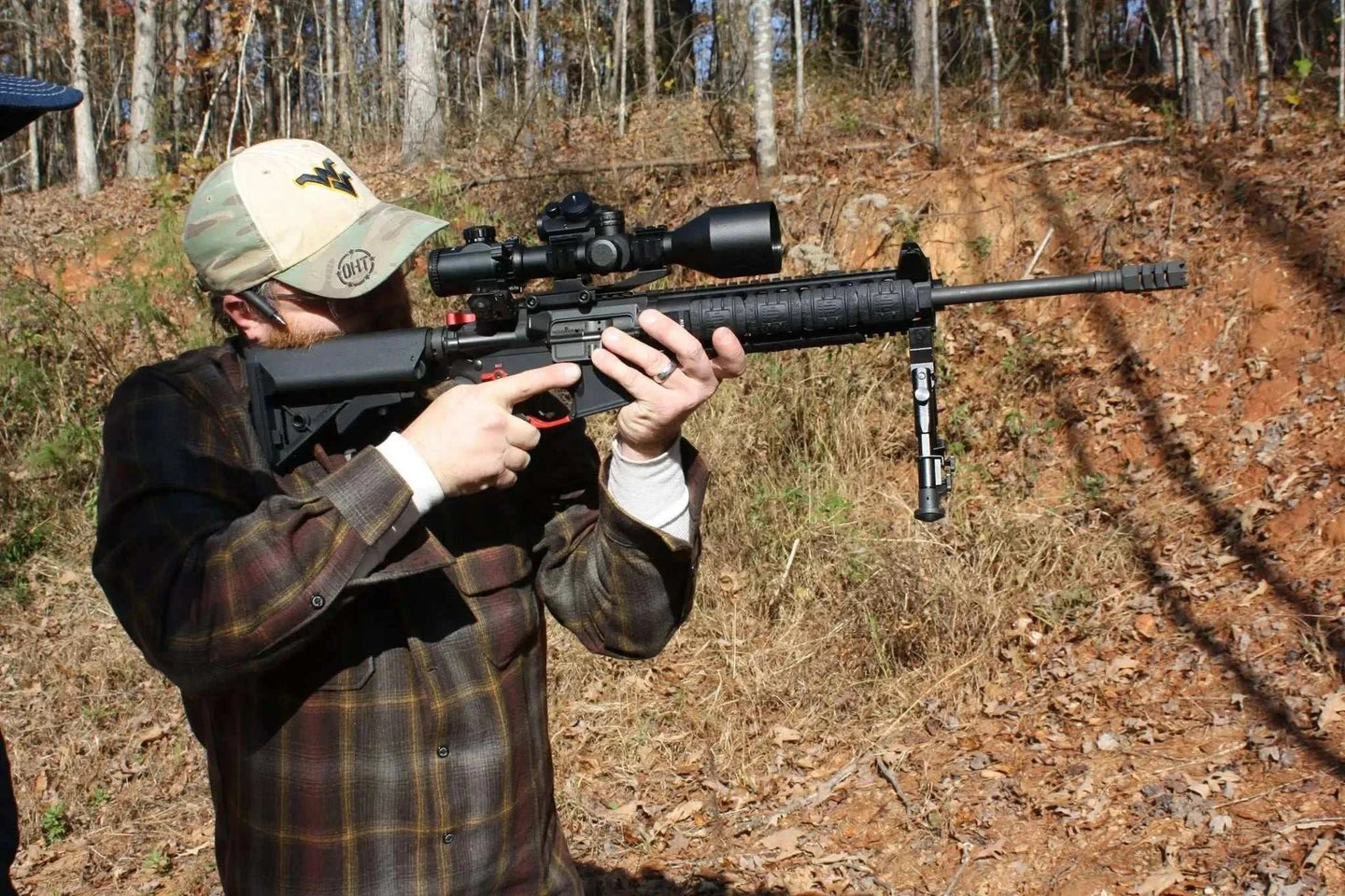 Man aiming rifle equipped with Osprey USA Elite Series 2.5-10x42MOA scope in outdoor setting
