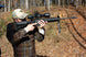 Man aiming rifle equipped with Osprey USA Elite Series 2.5-10x42MOA scope in outdoor setting