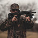 Tactical shooter holding rifle equipped with matte black vertical grip laser flashlight combo featuring 500-lumen light