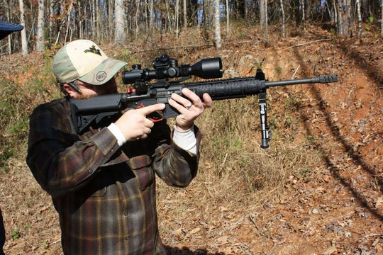 Man aiming rifle equipped with Osprey USA Elite Series 2.5-10x42MOA scope in outdoor setting